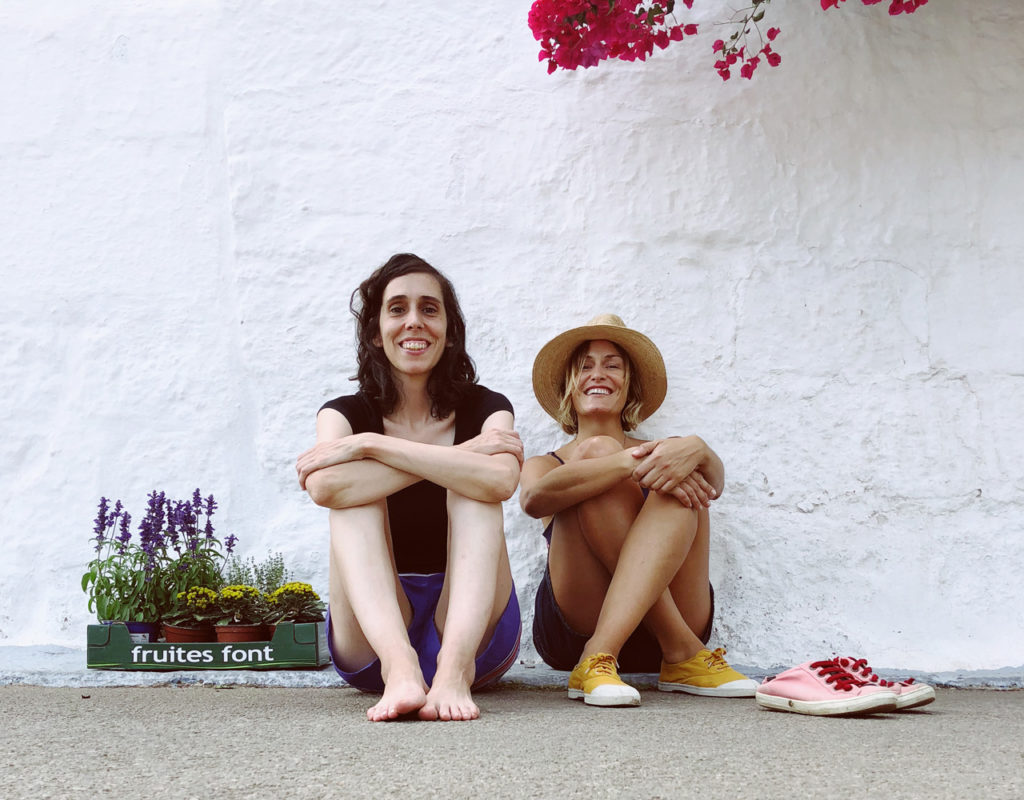 dos chicas sentadas suelo en pared blanca